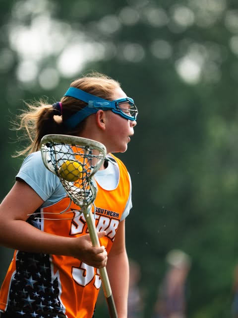 Player in orange Southern Stars jersey cradling ball